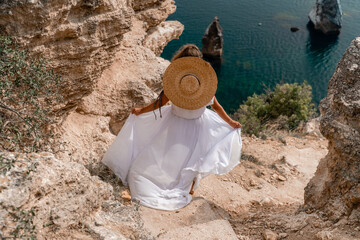 A girl with loose hair in a long white dress descends the stairs between the yellow rocks...