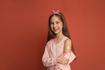A teenage girl with a patch on her arm after vaccination. The girl smiles. Space for text,...