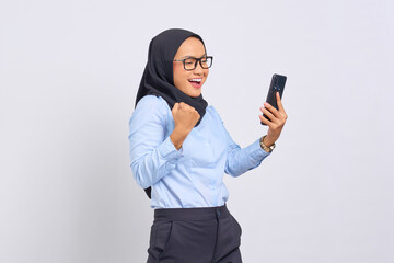 Portrait of excited young Asian woman celebrating with mobile phone isolated on white background