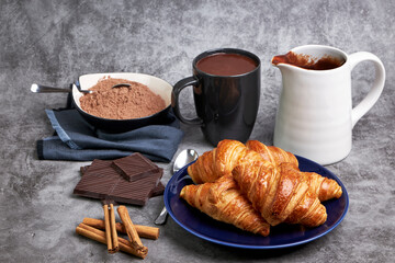 Pitcher of hot chocolate along with delicious croissants and various ingredients
