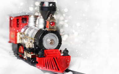 A Christmas train with a red cab rides on a light background