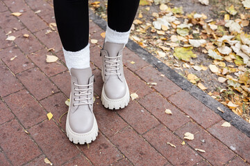 Stylish woman stands in beige shoes. Close-up of female legs in fashionable leather beige vintage boots. New seasonal collection of women's shoes