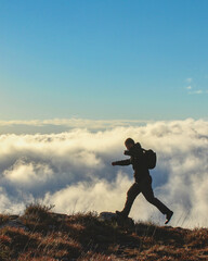 homem caminhando nas montanhas com nuvens ao fundo 