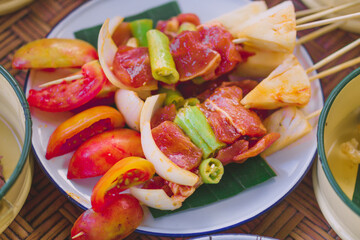 BBQ skewers in a white plate waiting to be grilled