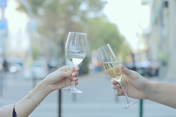 glasses of toast chin chin, hands with glasses of white wine in a street cafe