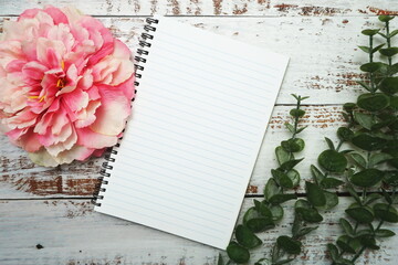 Naklejka premium Notebook with blank pages withh alarm clock and floweron wooden background