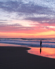 Fototapeta na wymiar pessoa caminhando na beira do mar durante nascer do sol 