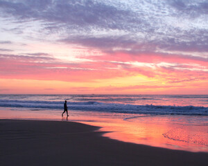 Fototapeta na wymiar pessoa caminhando na beira do mar durante nascer do sol 