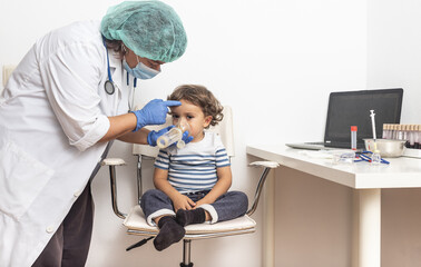 Obraz premium Paediatrician administers aerosolised medication while checking pneumonia in a blond Caucasian boy in a clinic.