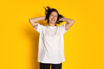 Portrait of smiling young beautiful girl in white t-shirt and jeans laughing isolated on yellow background