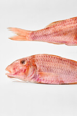 Head and tail with pinkish scales of air-dried salted surmullet on white