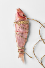 Salt-dried surmullet tied with rough string lying on white background