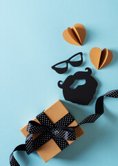 Fathers day concept with gift box and moustache and bread on blue background