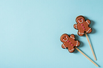 Two gingerbrad man on stick on blue background