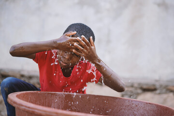 Malian boy wash face with clean water