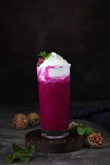 Fresh dragon fruit smoothies with milk, whipped cream and green mint leaves on vintage background