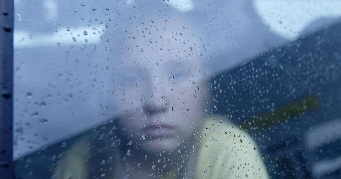 Little girl looking out from car window. Rainy weather.