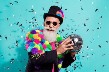 Photo of shiny funky mature showman dressed handmade pom-pom jacket holding disco ball isolated...