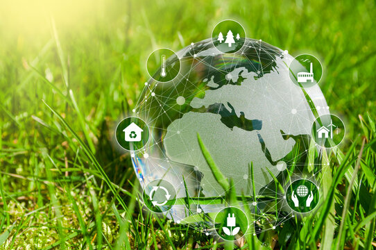 Globe made of glass with icons metaphor for ESG environment social governance on green grass