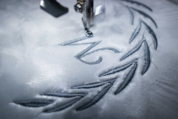 Monogram embroidery design with name on blanket. Embroidery machine with gray thread. Close up