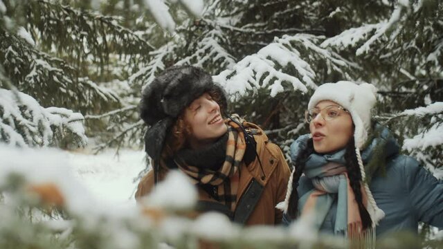 Two Young Cheerful Women Walking In Winter Forest, Chatting And Playing With Snow