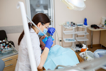 A dentist treats a male patient with dental instruments. The dentist examines the teeth of the patients in the dental clinic. Selective focus