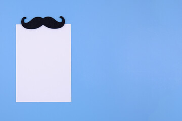 A spring-loaded notebook with a retro black mustache on a blue background.The layout of a greeting card for Father's Day, Boss's Day,Dad's or grandpa's birthday,a barbershop price list template.