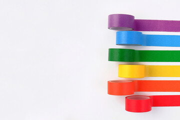 Multicolored rolls of rainbow adhesive tape on the side on a white background.A set of bright sticky decorative ribbons for creativity, gift box packaging, for making postcards.Copyspace