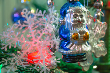 A toy on the Christmas tree Santa Claus. Christmas toys on the green branches of the Christmas tree. Decorations and a burning garland on the Christmas tree.