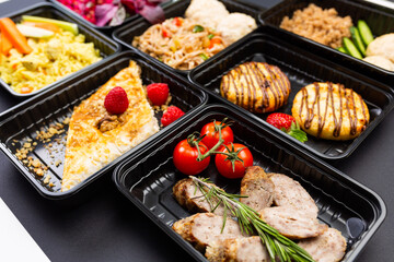 Ready healthy food catering menu in lunch boxes meat and vegetable packages on black table background