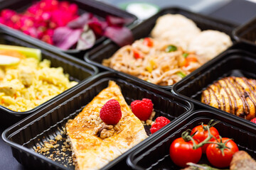 Ready healthy food catering menu in lunch boxes meat and vegetable packages on black table background