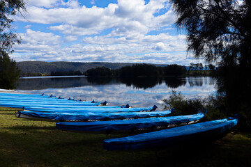 Line of blue rowing boats on the shoreline of the Penrith Lakes with mirror like reflection off the...