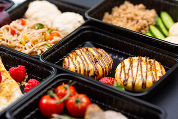 Ready healthy food catering menu in lunch boxes meat and vegetable packages on black table...