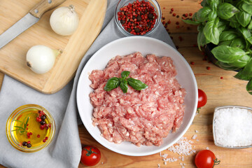 Raw chicken minced meat and ingredients on wooden table, flat lay