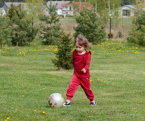 Mała dziewczynka gra w piłkę na zielonej łące - obrazy, fototapety, plakaty
