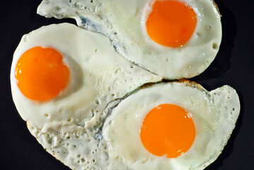 Scrambled eggs in a black plate. Fried eggs on an old concrete table.