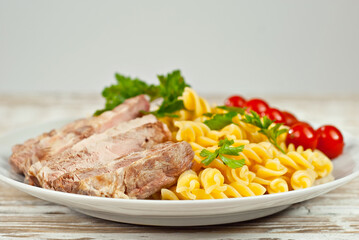Pasta with meat and tomatoes in a white plate. Pasta on a shabby wooden table.