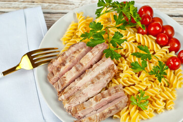 Pasta with meat and tomatoes in a white plate. Pasta on a shabby wooden table.
