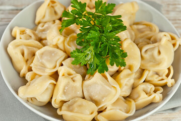 Dumplings in a white plate on an old shabby table. Dumplings with yellow dough close up. Food on a white board background.