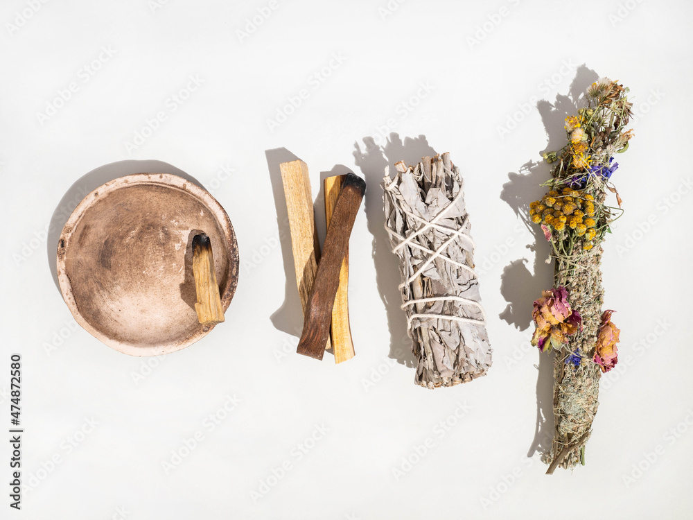 Wall mural items for spiritual cleansing - sage and aromatic herbs bundle and palo santo incense sticks on whit