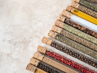 Various dry spices in glass tubes on textured background.