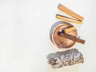 Items for spiritual cleansing - sage bundle, palo santo incense sticks on white background.