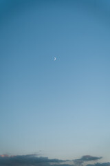 Crescent moon on a blue sky above the clouds