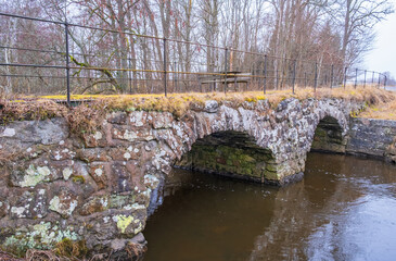 Old arch bridge with a rest area over a river