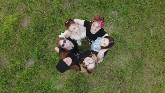 Friendly girls hug and wave their hands to us. View from above.