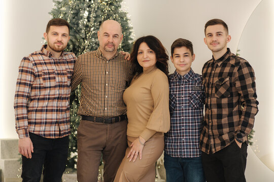 Mother and father with their three sons smile. Big family of four man and one woman. Chrismas feiry tail