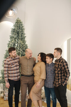 Mother and father with their three sons smile. Big family of four man and one woman. Chrismas feiry tail