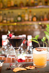 refreshing alcoholic drink with berries, ice vodka and gin, lemon peel served in glass cup on the counter on blurred background