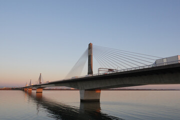 晴天下の湾岸木曽川橋を渡るトラックの群れ
