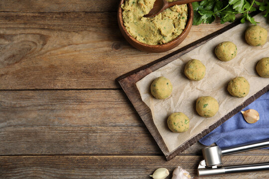 Raw falafel balls and ingredients on wooden table, flat lay. Space for text